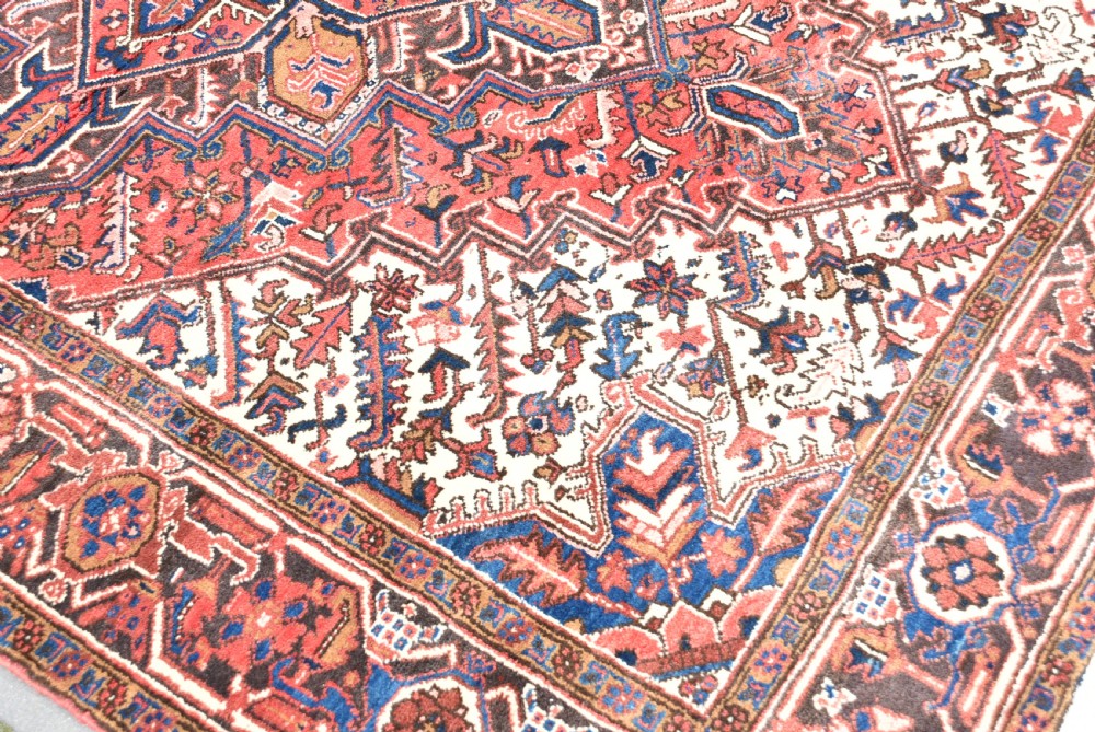 A rectangular hand-knotted Persian wool rug featuring a large geometric central medallion in navy and terracotta over a cream field with patterned borders. View VIII