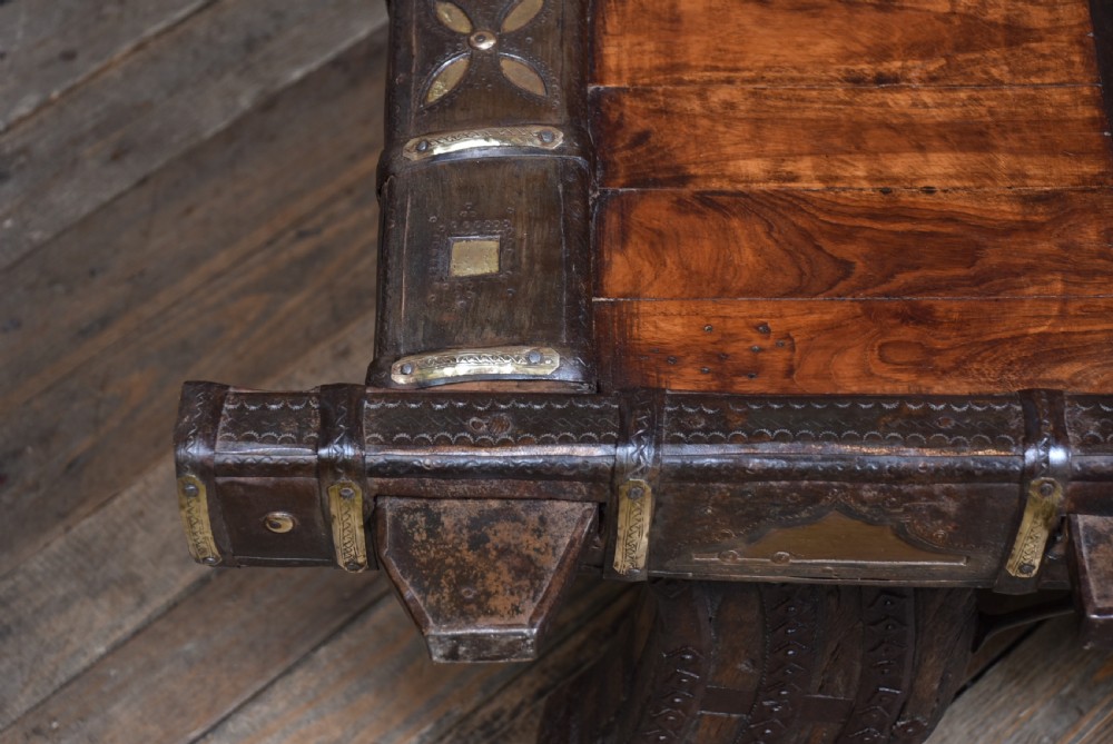 A low square coffee table crafted from a dark reclaimed bullock cart frame with decorative brass studding and stout carved legs. View VIII