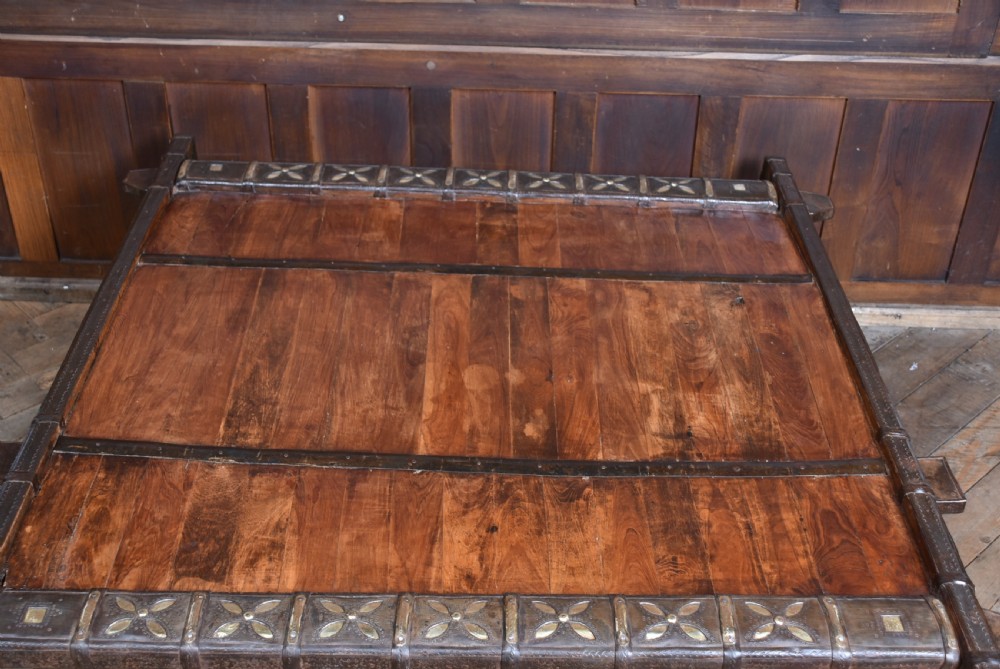 A low square coffee table crafted from a dark reclaimed bullock cart frame with decorative brass studding and stout carved legs. View XII
