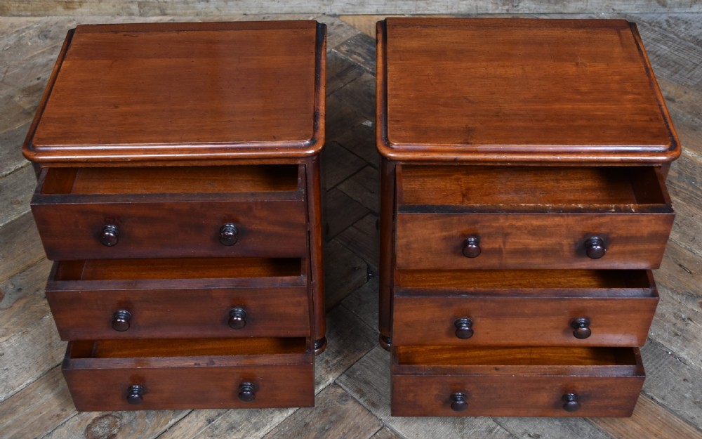 A pair of miniature mahogany chests of drawers, each featuring three drawers with turned wooden knobs and small turned feet. View V