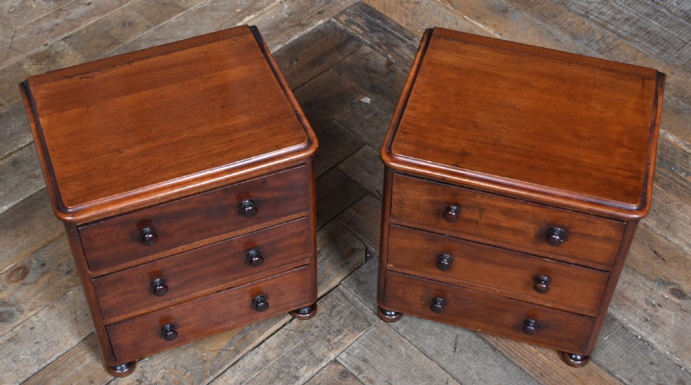 A pair of miniature mahogany chests of drawers, each featuring three drawers with turned wooden knobs and small turned feet. View VI