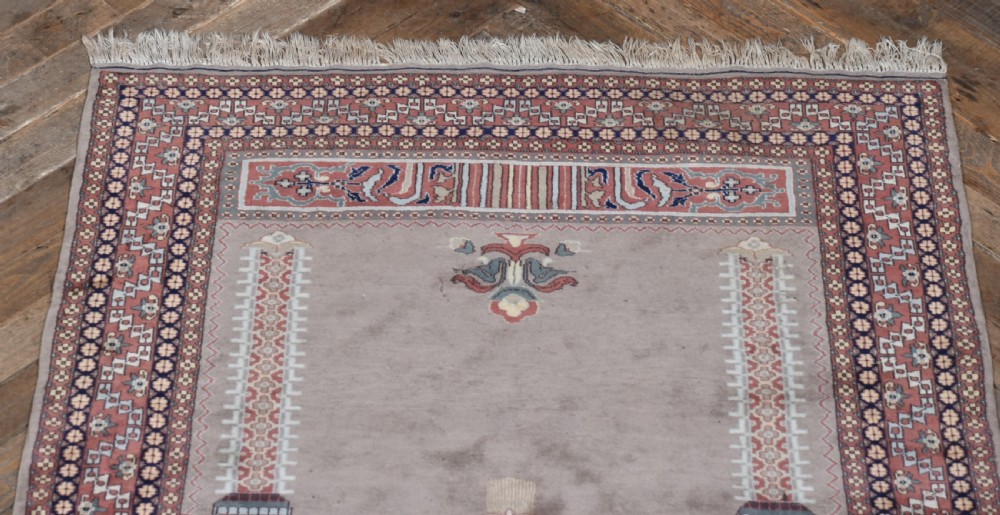 A hand-woven silk prayer rug featuring a central arched mihrab motif in taupe, framed by intricate terracotta and slate blue geometric floral borders with fringe at both ends. View IV