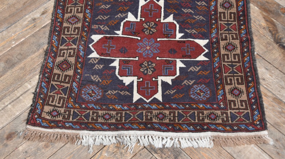 A hand-knotted vintage Oriental wool rug featuring geometric stepped medallions in terracotta red and cream set against a dark navy blue field with detailed tribal borders. View II