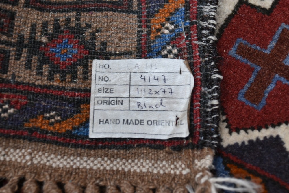 A hand-knotted vintage Oriental wool rug featuring geometric stepped medallions in terracotta red and cream set against a dark navy blue field with detailed tribal borders. View VIII