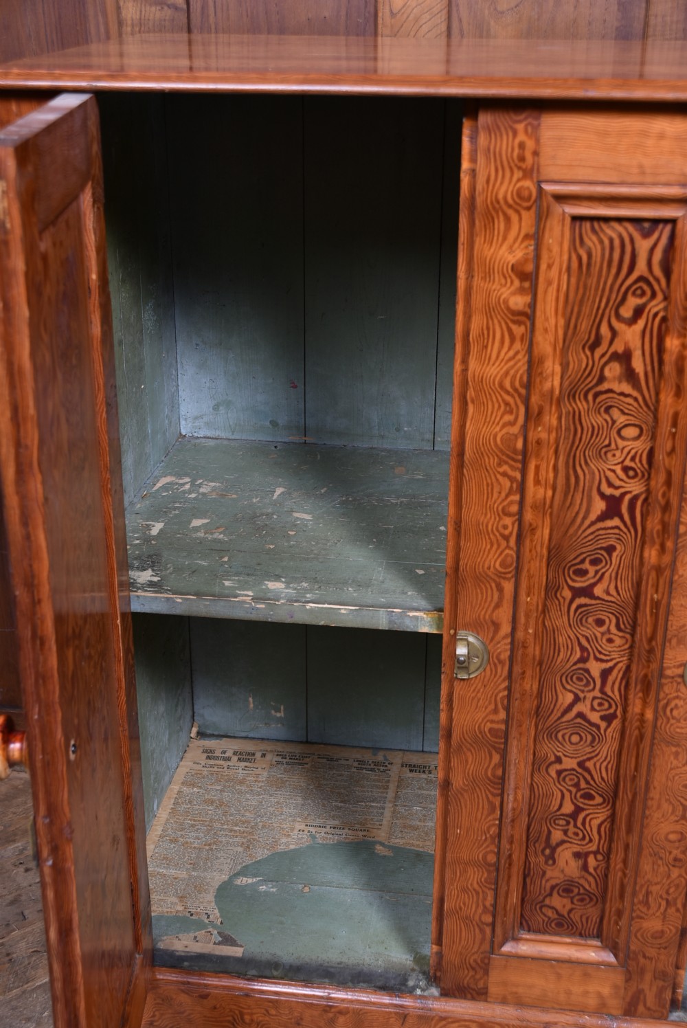 A Victorian Hungarian ash cupboard featuring highly figured swirling veneer panels, turned wooden knobs, brass keyhole escutcheons, and a solid plinth base. View IX