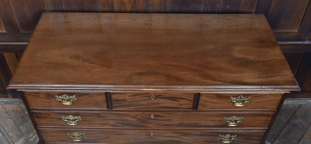 A Georgian style dark mahogany lowboy featuring five drawers with brass handles, a carved apron, and cabriole legs with ball and claw feet. View X