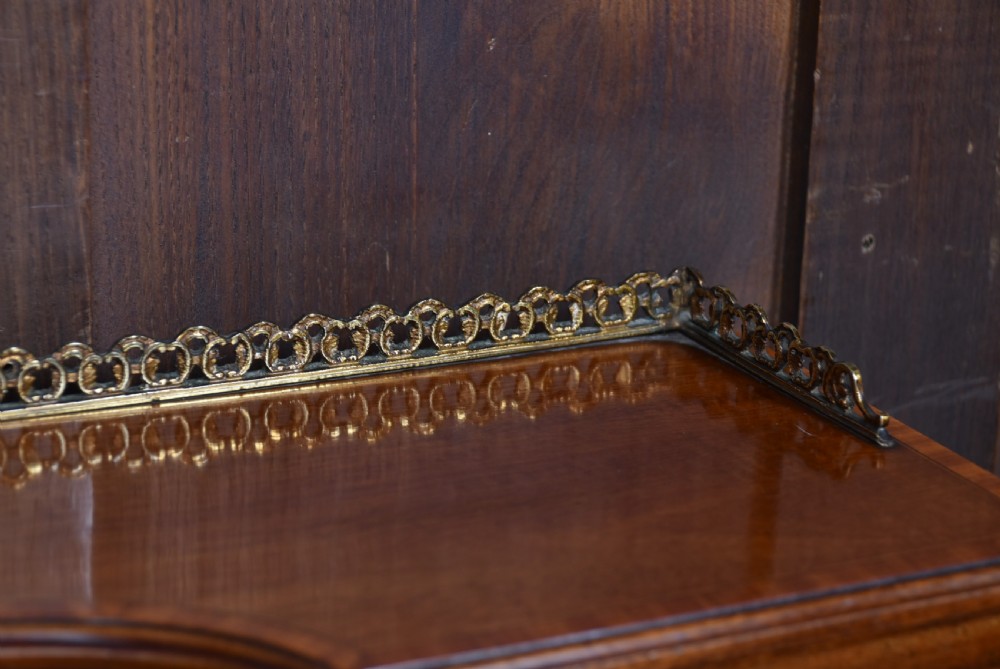 An Edwardian mahogany writing desk featuring a leather writing surface, inlaid drawer fronts, a brass gallery, and slim tapered legs on castors. View VIII