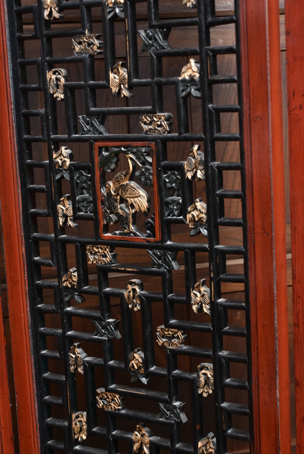 A four-panel tall folding room screen featuring red-lacquered timber framing, intricate black lattice fretwork, and carved gilded lower panels. View III