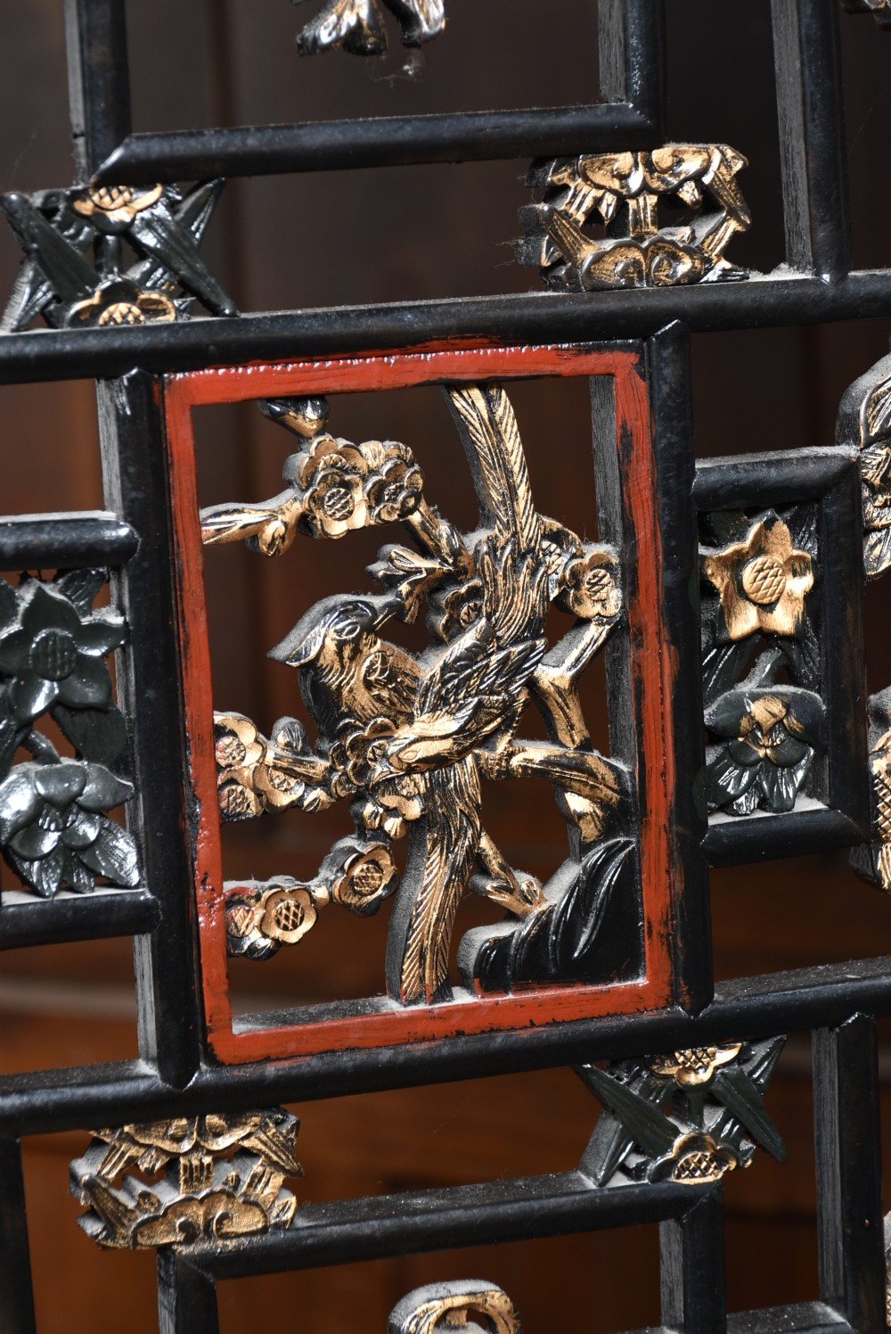 A four-panel tall folding room screen featuring red-lacquered timber framing, intricate black lattice fretwork, and carved gilded lower panels. View V