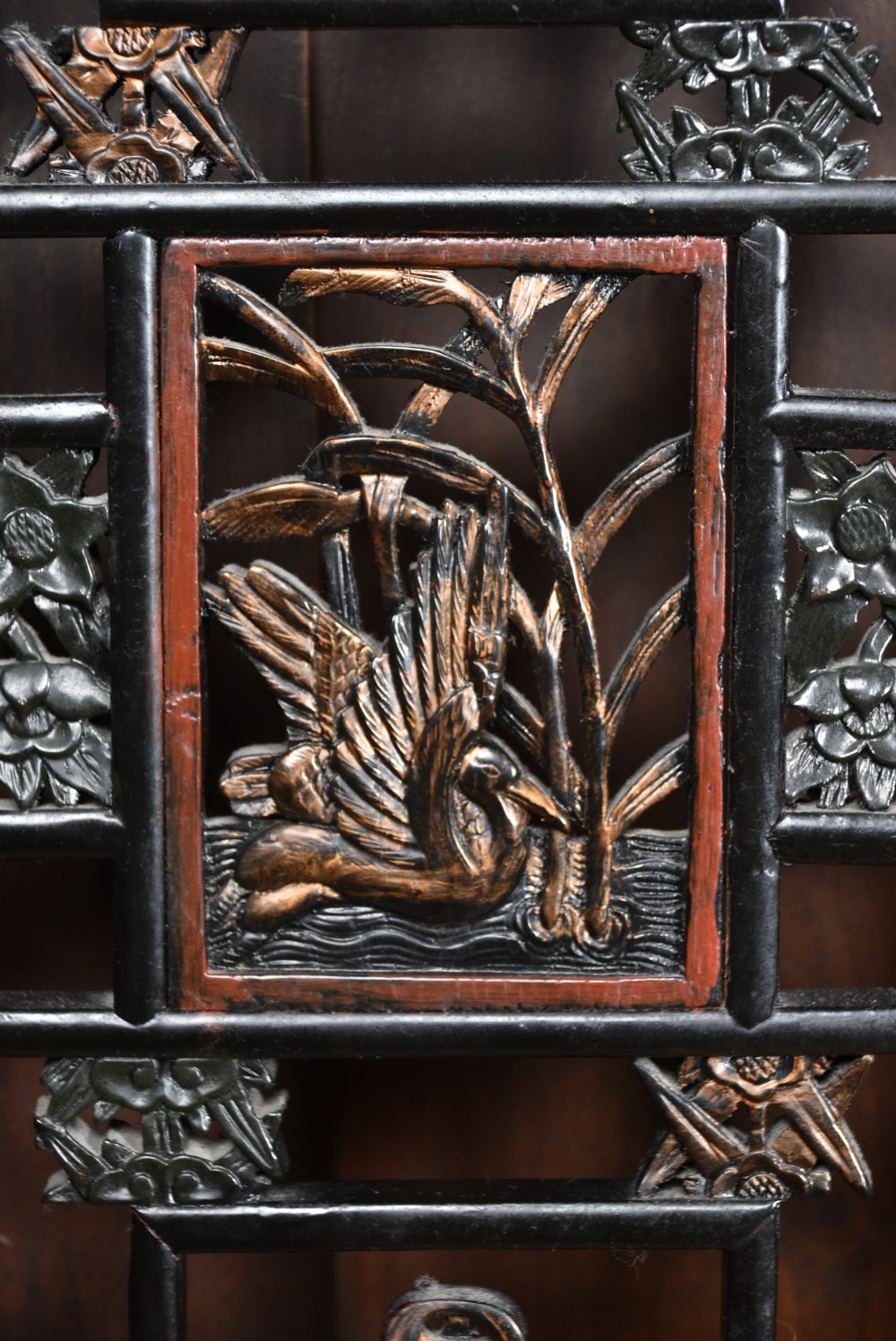 A four-panel tall folding room screen featuring red-lacquered timber framing, intricate black lattice fretwork, and carved gilded lower panels. View XVII