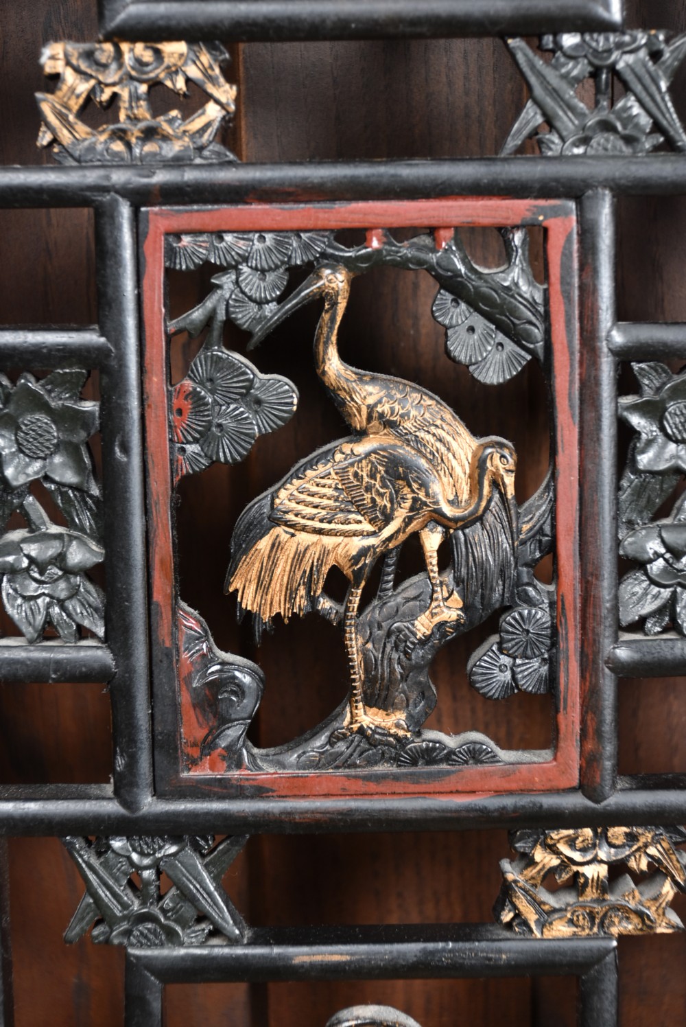 A four-panel tall folding room screen featuring red-lacquered timber framing, intricate black lattice fretwork, and carved gilded lower panels. View XVIII