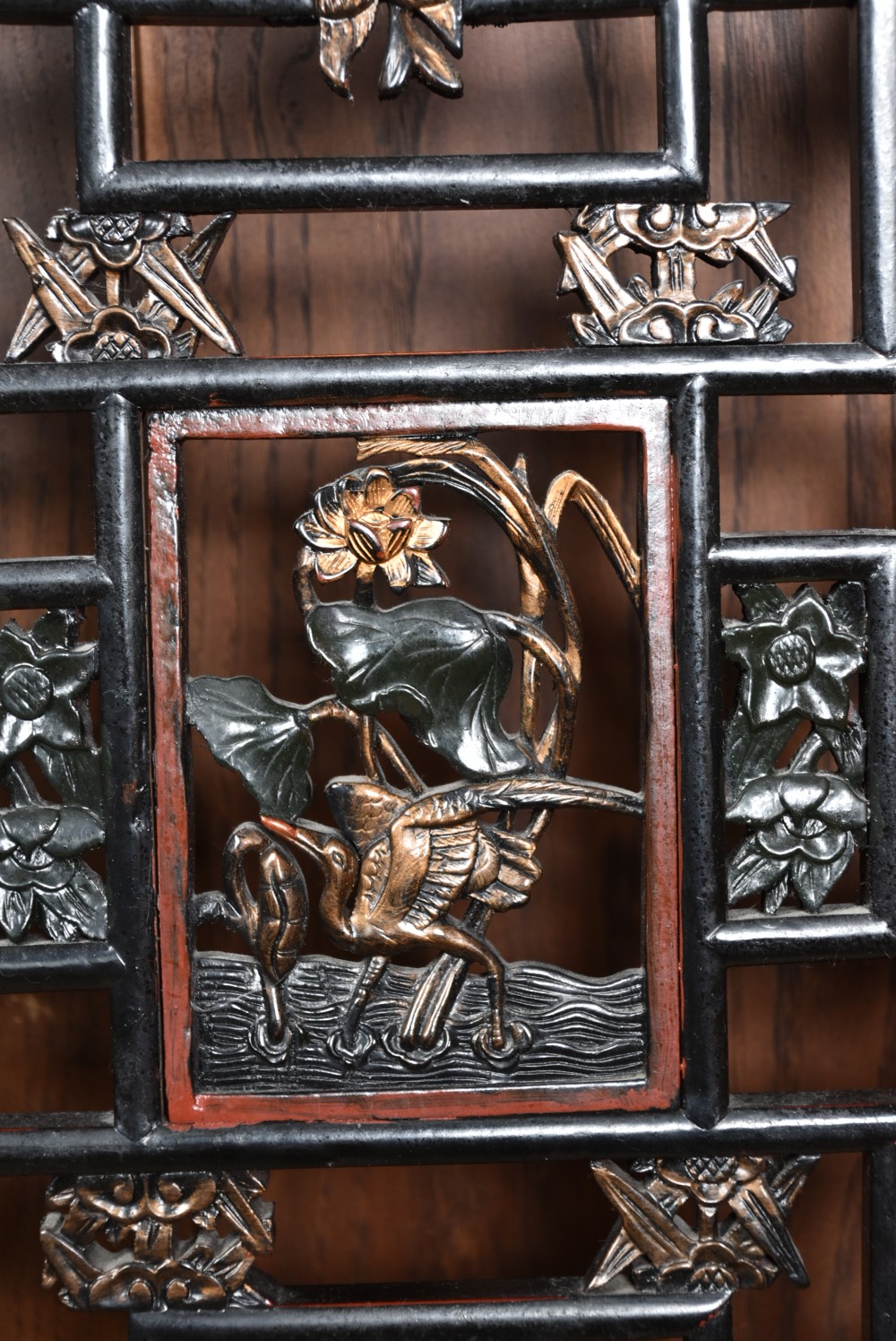 A four-panel tall folding room screen featuring red-lacquered timber framing, intricate black lattice fretwork, and carved gilded lower panels. View XX
