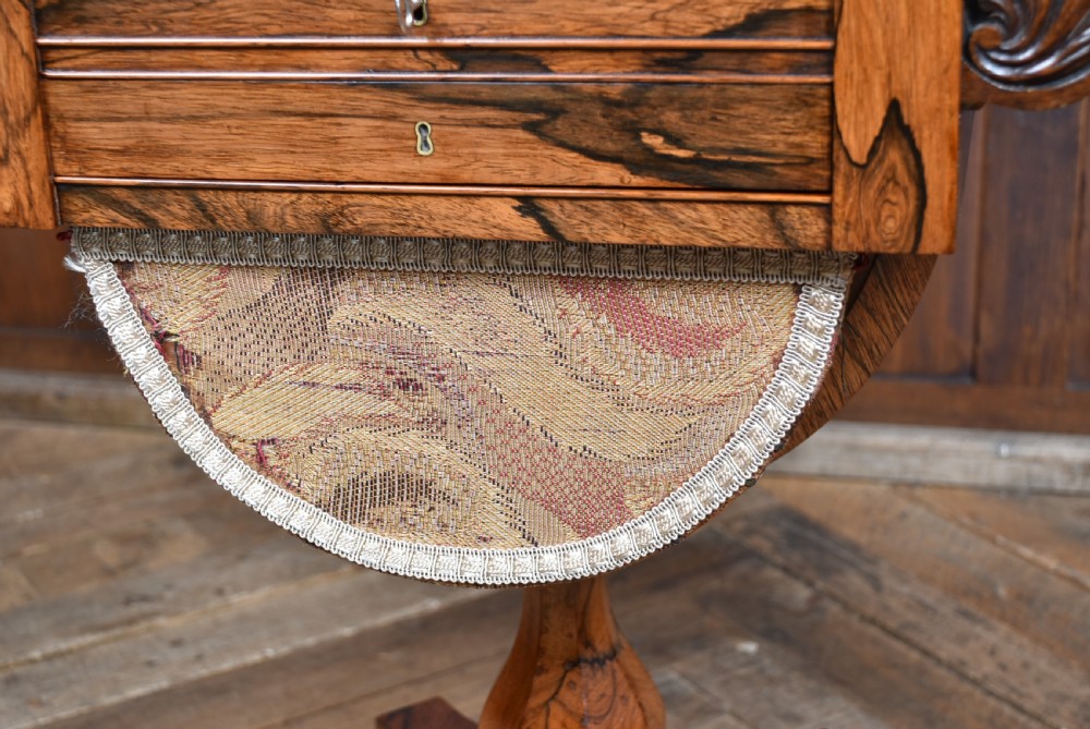 A Victorian rosewood drop-leaf work table featuring a turned column, fabric-covered sewing basket underneath, and a quadform base with scroll feet. View IX