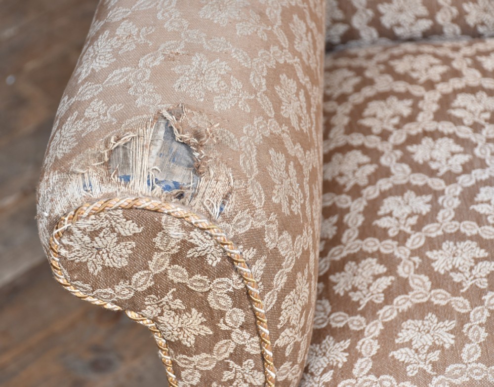A 19th-century wingback armchair upholstered in patterned beige fabric, supported on front cabriole legs with pad feet. View IV