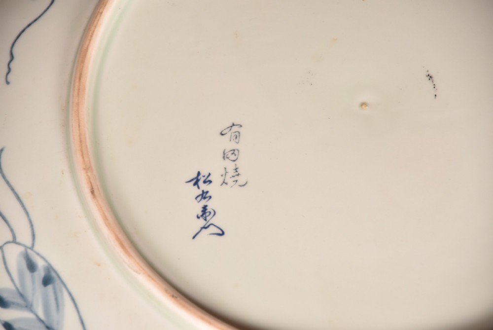 A circular Japanese Imari porcelain charger plate featuring a central landscape roundel surrounded by iron red and cobalt blue floral reserves. View IX