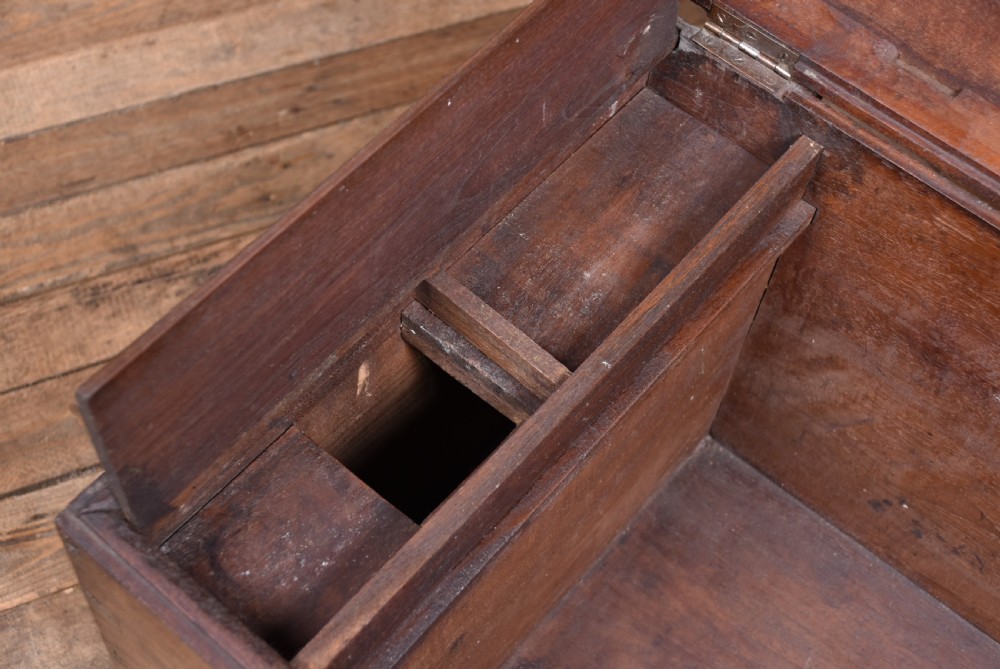 A 19th-century dark teak storage chest featuring detailed relief carving of figures and architecture on the front and side panels, complete with brass latches and corner straps. View XVII