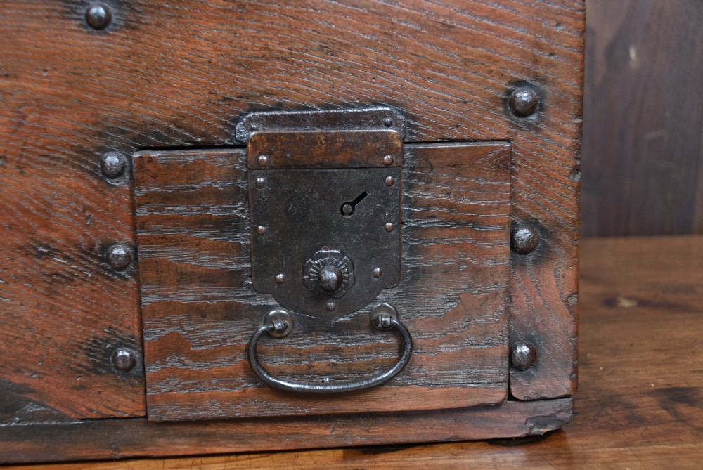 A heavy Japanese dark wooden zenibako money box reinforced with iron studs and featuring a top coin slot. View X