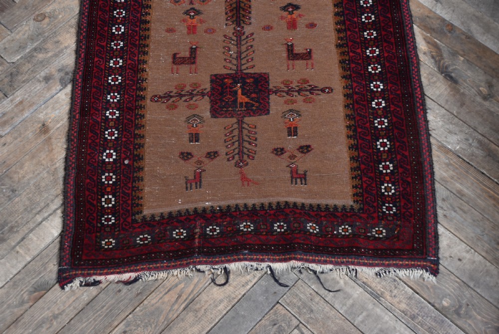 A handwoven vintage Iranian rug featuring a light brown central field decorated with animal and bird motifs framed by dark red geometric borders. View II