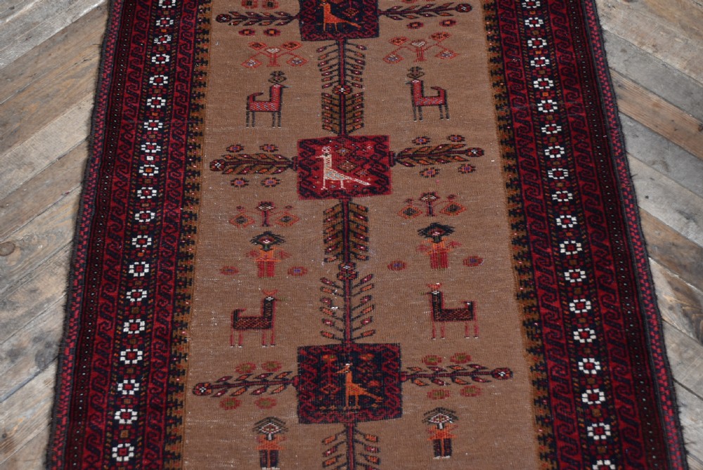 A handwoven vintage Iranian rug featuring a light brown central field decorated with animal and bird motifs framed by dark red geometric borders. View III