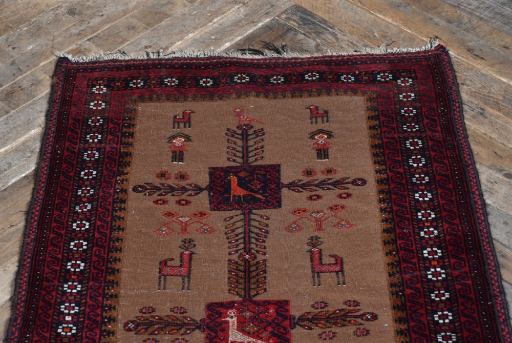 A handwoven vintage Iranian rug featuring a light brown central field decorated with animal and bird motifs framed by dark red geometric borders. View V