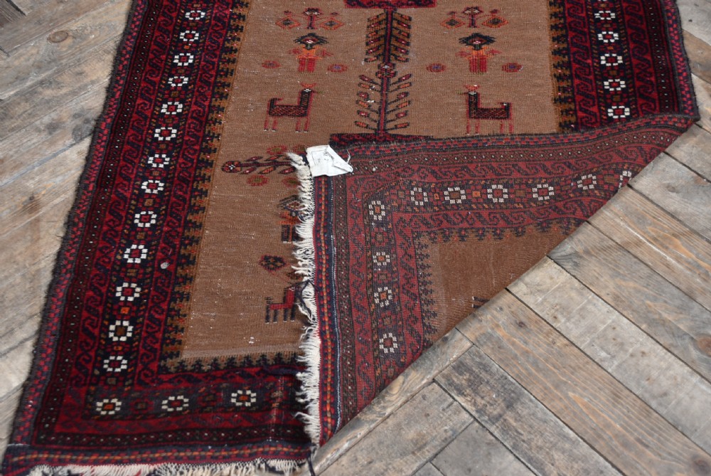 A handwoven vintage Iranian rug featuring a light brown central field decorated with animal and bird motifs framed by dark red geometric borders. View VII