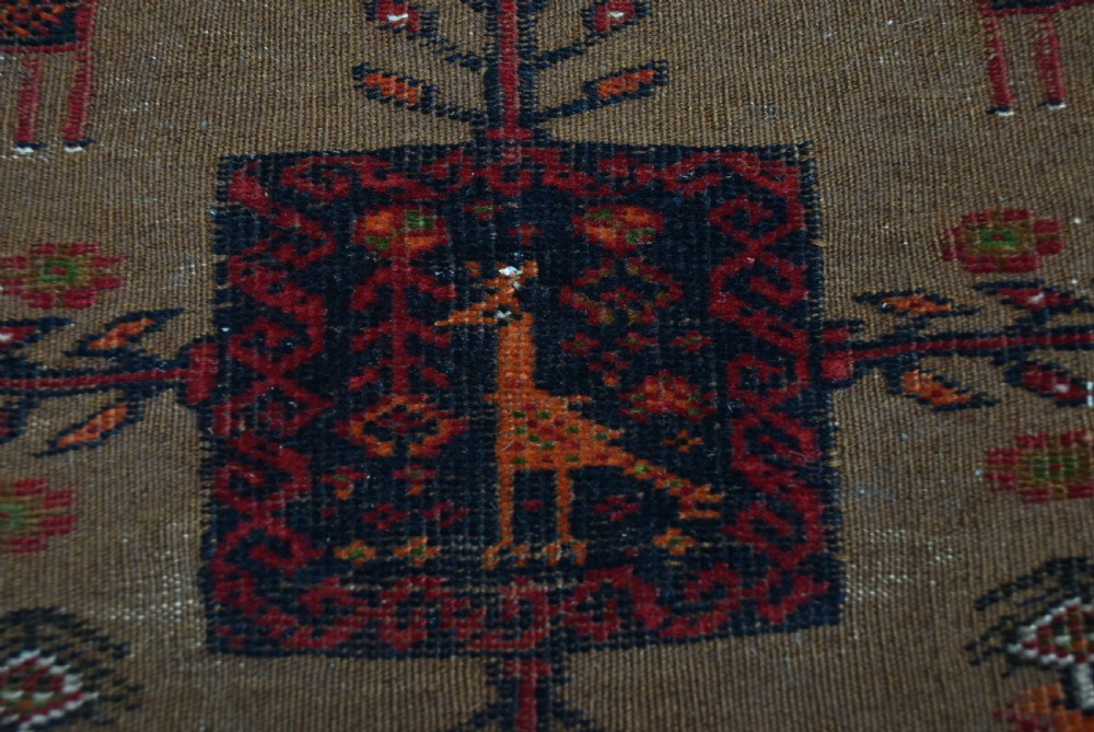 A handwoven vintage Iranian rug featuring a light brown central field decorated with animal and bird motifs framed by dark red geometric borders. View IX