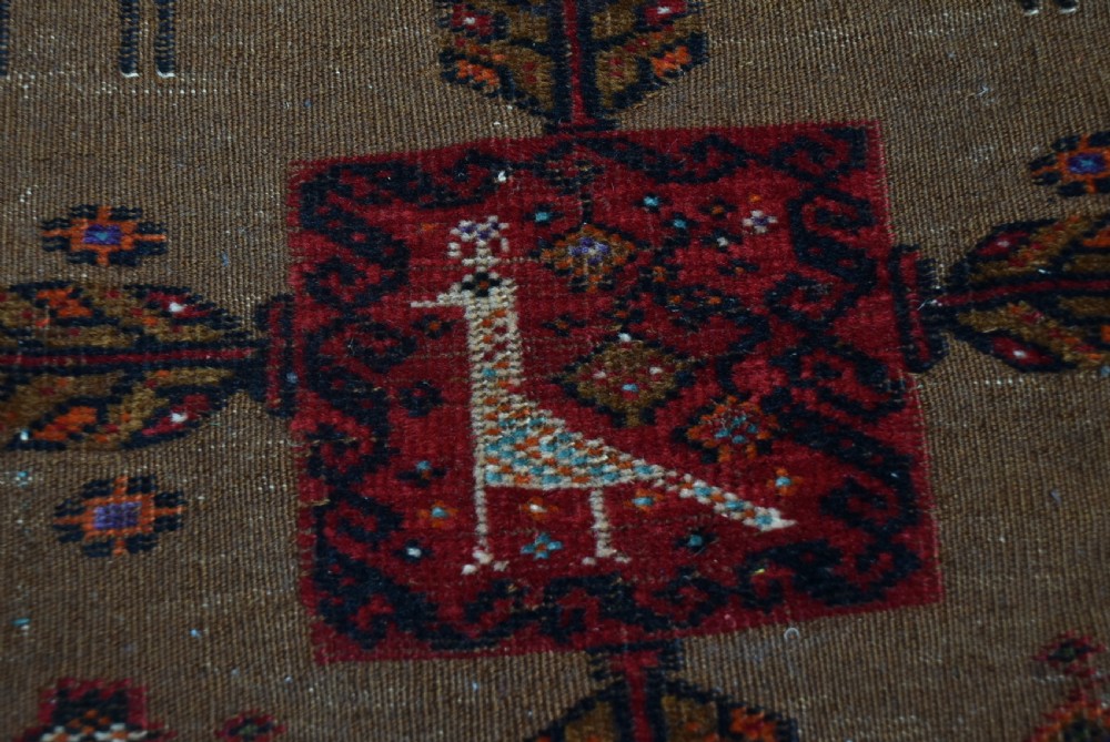 A handwoven vintage Iranian rug featuring a light brown central field decorated with animal and bird motifs framed by dark red geometric borders. View XI