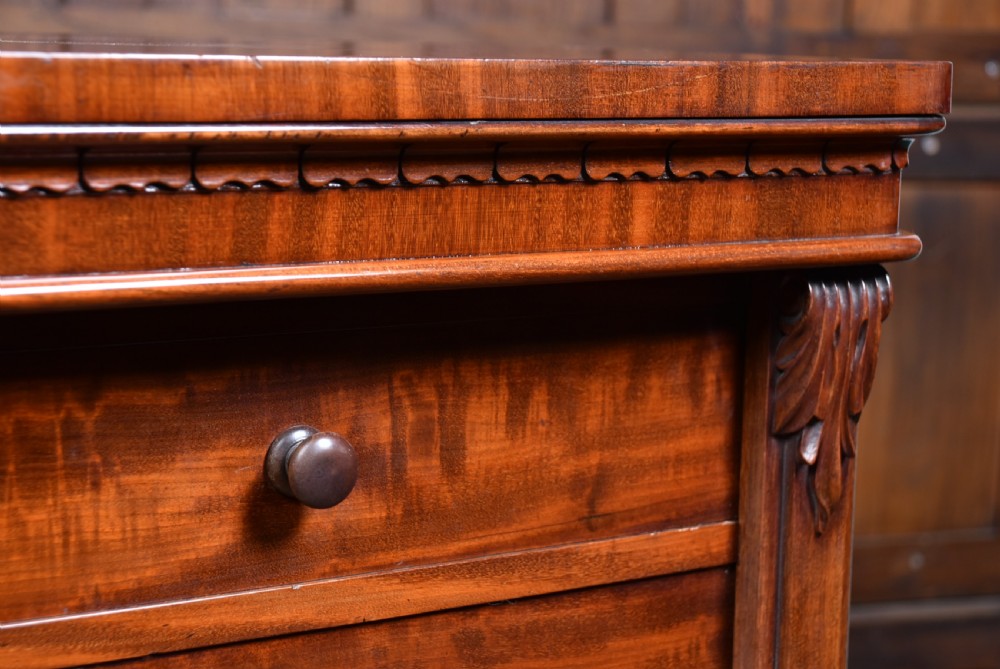 A tall Victorian mahogany Wellington chest featuring seven graduated drawers, turned knobs, carved corbels, and a hinged side locking bar on a plinth base. View V