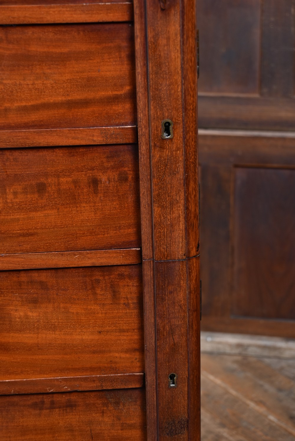A tall Victorian mahogany Wellington chest featuring seven graduated drawers, turned knobs, carved corbels, and a hinged side locking bar on a plinth base. View VI