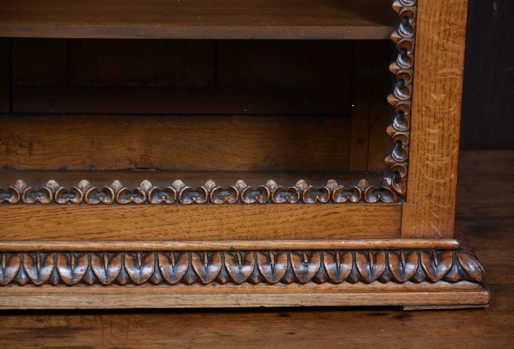 A Victorian oak counter-top display cabinet featuring carved border trim, interior wooden shelves, a glazed front, and a top brass keyhole. View VI