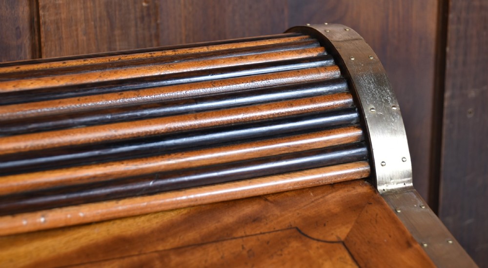 A nineteenth-century camphor wood roll-top writing box with brass-bound corners, a central brass cartouche, and a slatted tambour top. View V