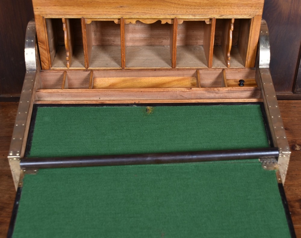 A nineteenth-century camphor wood roll-top writing box with brass-bound corners, a central brass cartouche, and a slatted tambour top. View XI