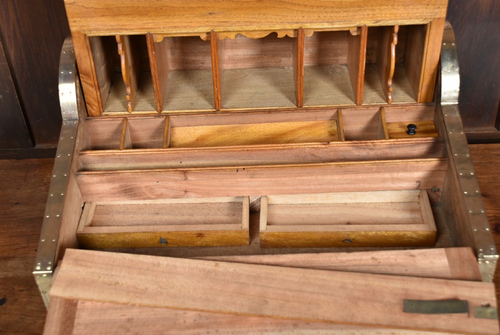 A nineteenth-century camphor wood roll-top writing box with brass-bound corners, a central brass cartouche, and a slatted tambour top. View XVI