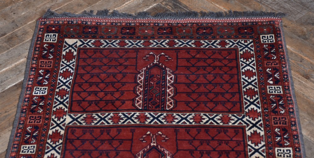 A handwoven red wool rug featuring double arched niche motifs, geometric border patterns, dark navy details, and fringe ends. View II