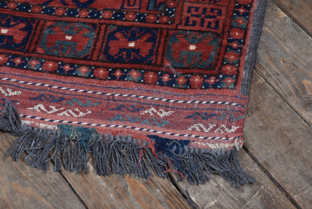 A handwoven red wool rug featuring double arched niche motifs, geometric border patterns, dark navy details, and fringe ends. View VI