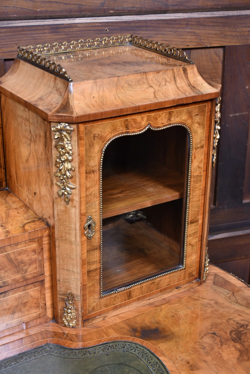 Victorian burr walnut writing desk featuring cabriole legs, brass mounts, an inset leather writing top, and an upper superstructure with glazed side cabinets and a central mirror. View VIII