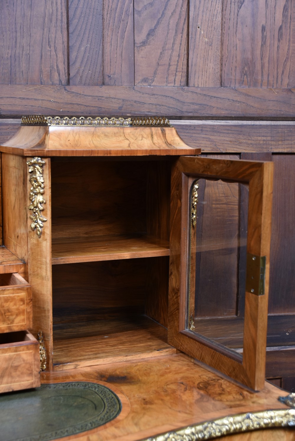 Victorian burr walnut writing desk featuring cabriole legs, brass mounts, an inset leather writing top, and an upper superstructure with glazed side cabinets and a central mirror. View XIII