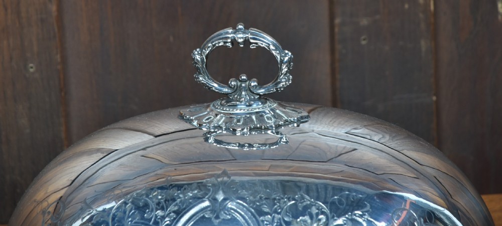 A pair of domed silver-plated meat covers featuring ornate cast handles, beaded lower rims, and engraved foliate cartouches. View V