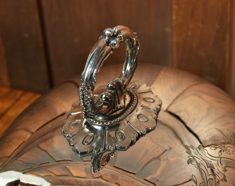 A pair of domed silver-plated meat covers featuring ornate cast handles, beaded lower rims, and engraved foliate cartouches. View X