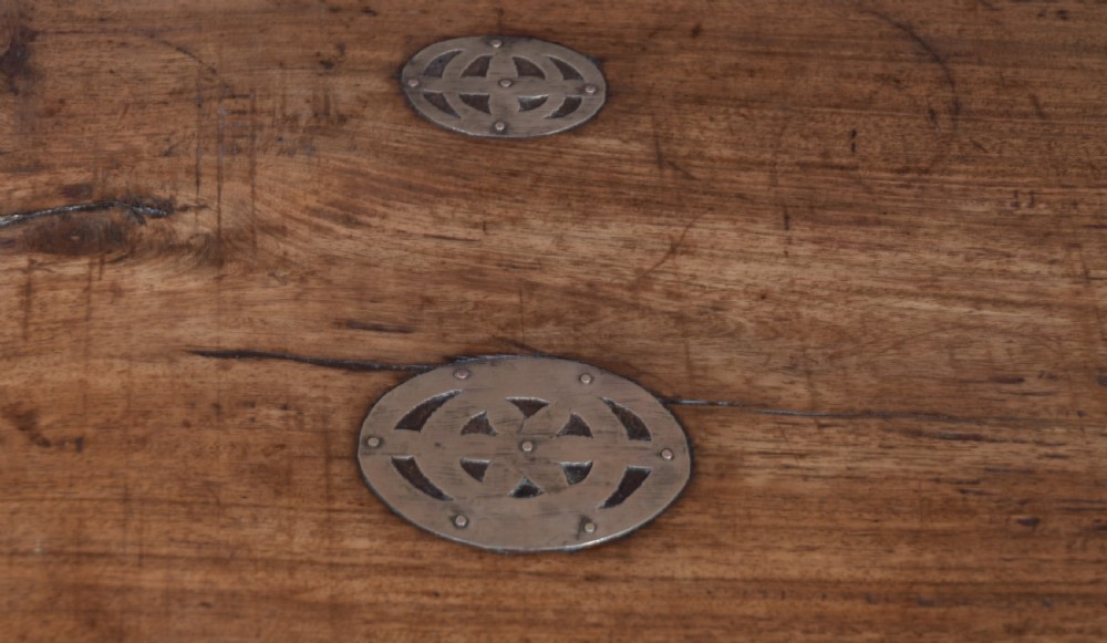 A low rectangular carved wood storage chest featuring decorative brass mounts, corner brackets, studs, and a central relief carving of a floral motif. View V
