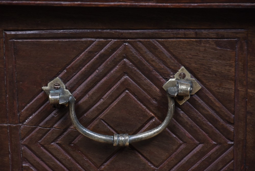 A low rectangular carved wood storage chest featuring decorative brass mounts, corner brackets, studs, and a central relief carving of a floral motif. View XIII
