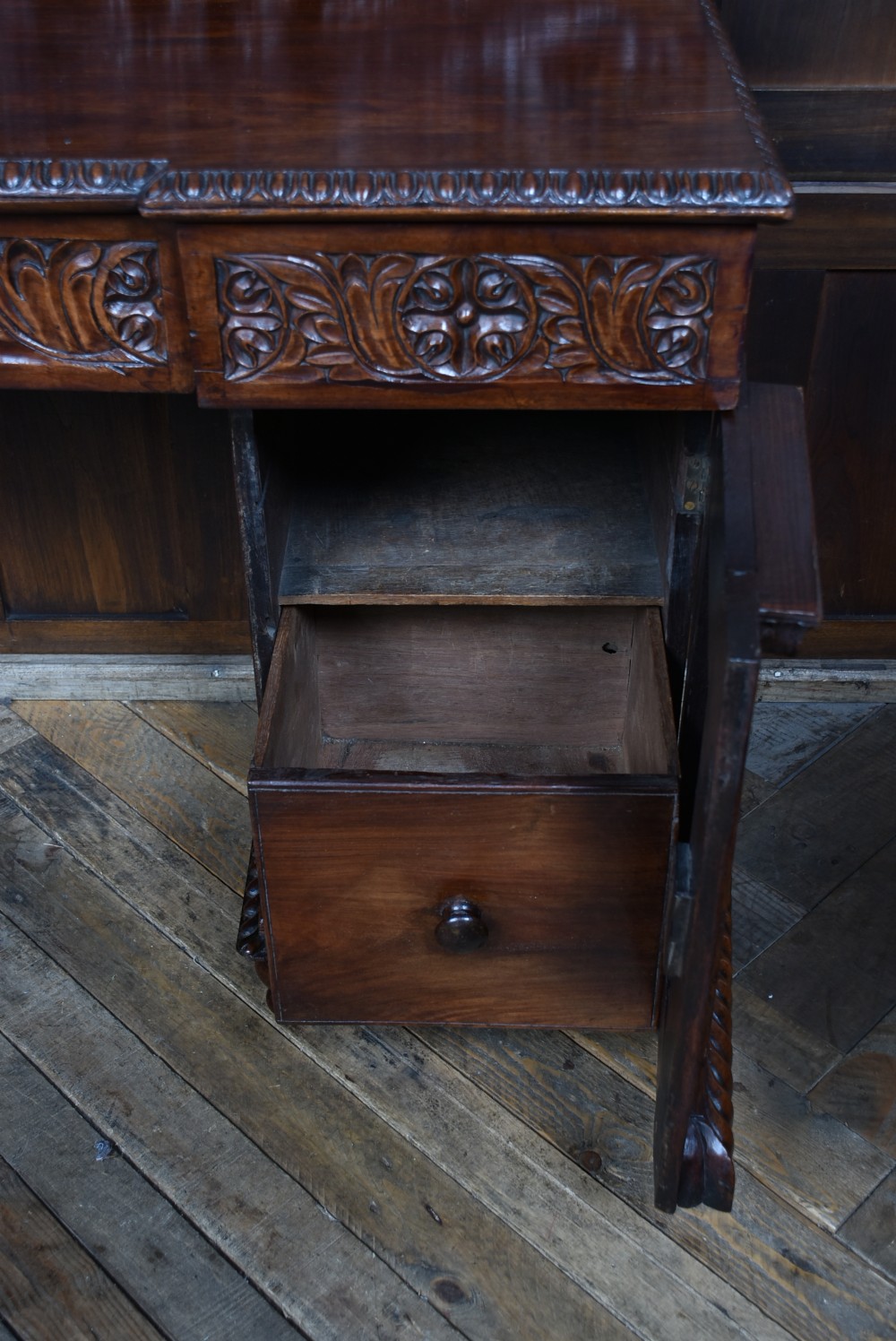 A carved dark padouk wood Anglo-Indian sideboard featuring an ornate foliage gallery top, carved frieze drawers, and two sunburst pedestal doors on turned bun feet. View VIII