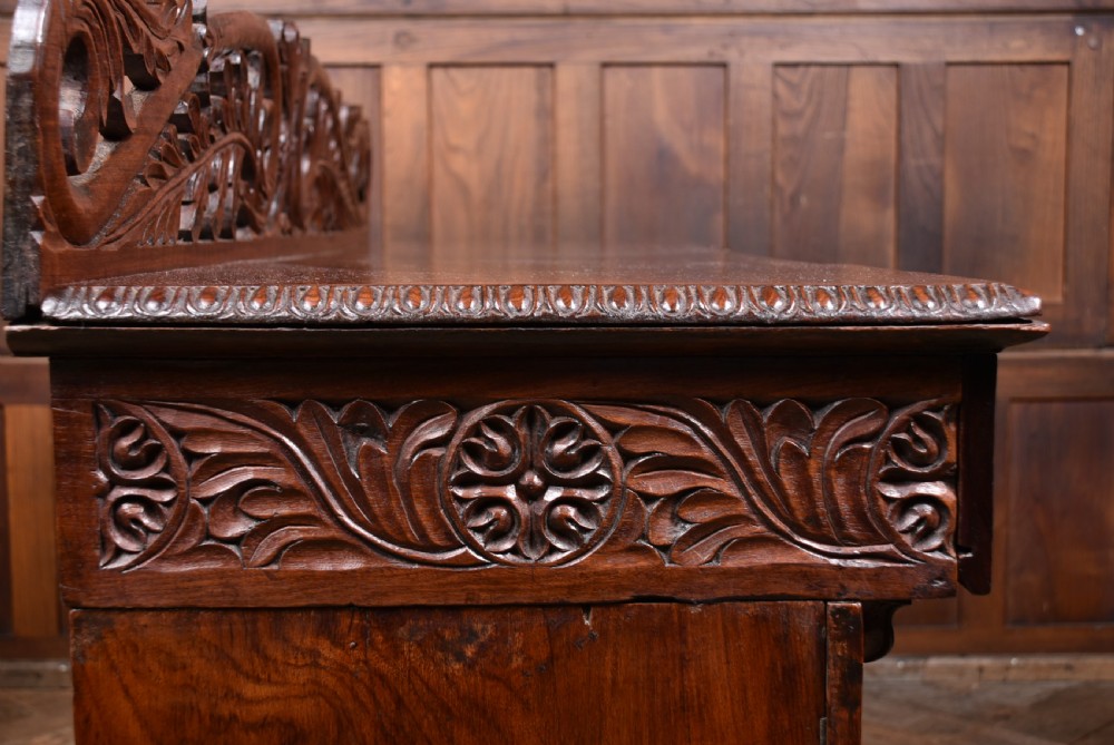 A carved dark padouk wood Anglo-Indian sideboard featuring an ornate foliage gallery top, carved frieze drawers, and two sunburst pedestal doors on turned bun feet. View XIII
