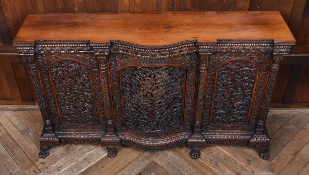 An Anglo-Indian dark padouk wood sideboard featuring intricate pierced openwork floral carvings across three arched cabinet doors and carved feet. View III