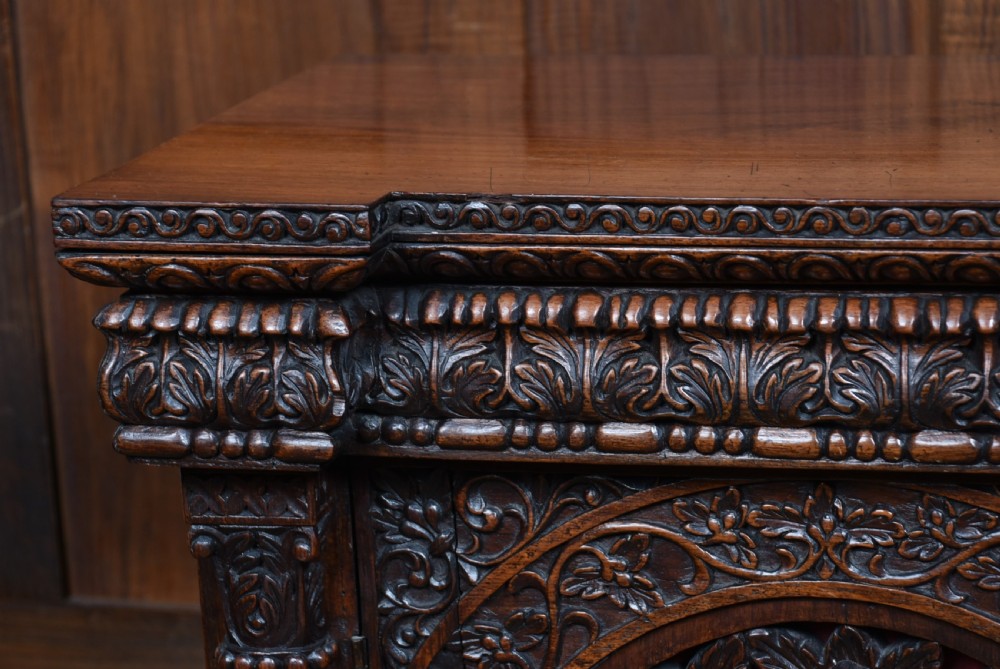 An Anglo-Indian dark padouk wood sideboard featuring intricate pierced openwork floral carvings across three arched cabinet doors and carved feet. View VIII