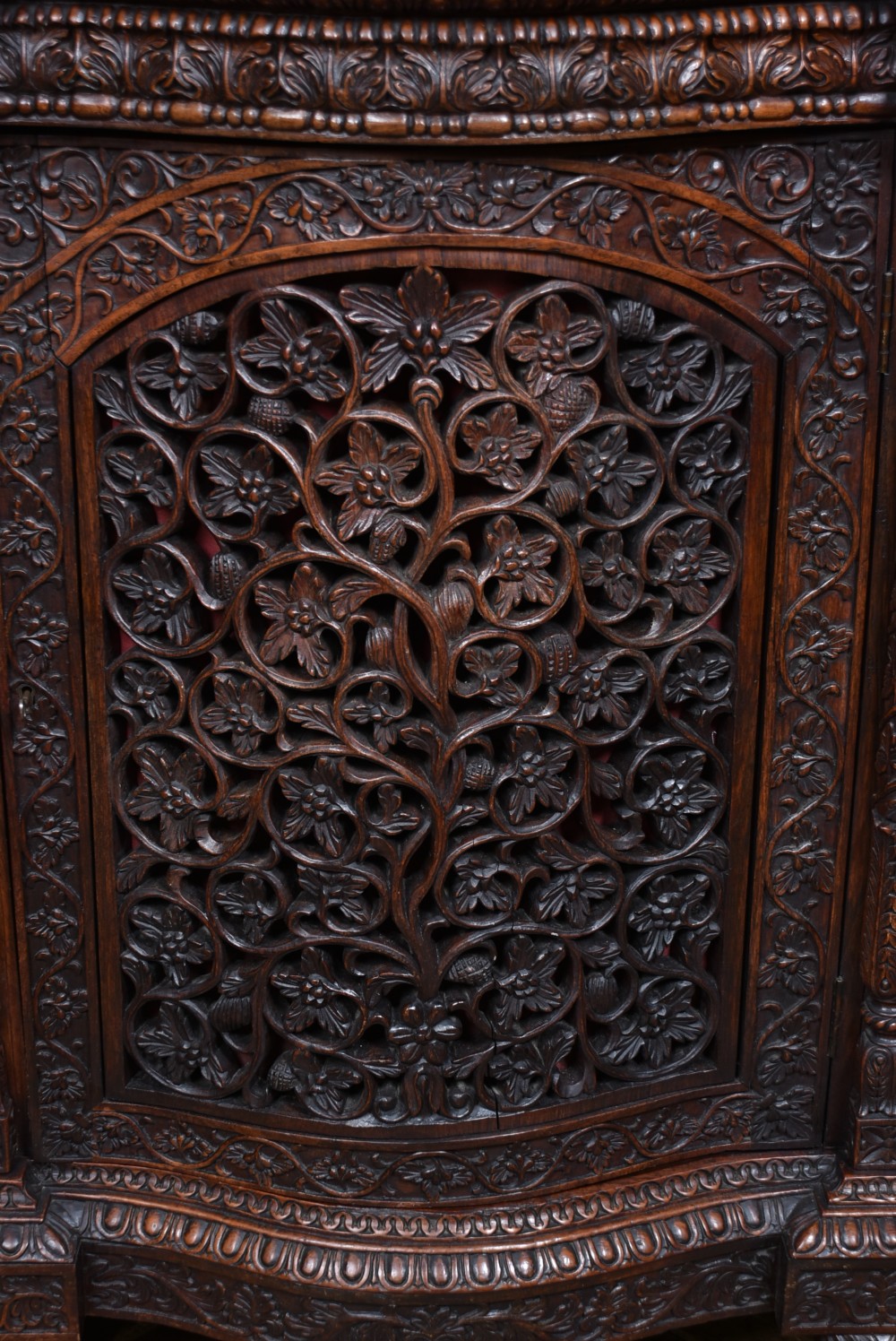 An Anglo-Indian dark padouk wood sideboard featuring intricate pierced openwork floral carvings across three arched cabinet doors and carved feet. View IX