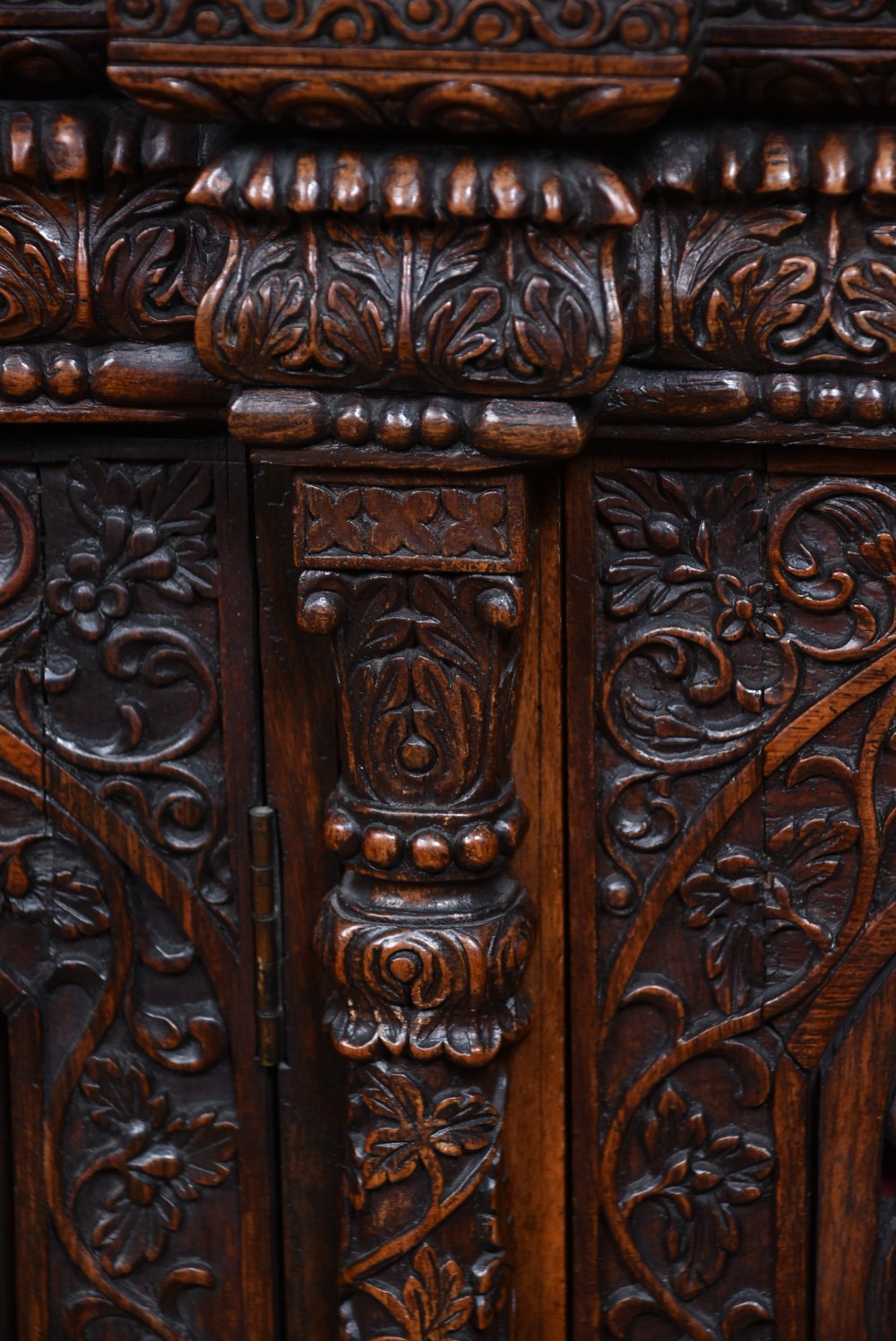 An Anglo-Indian dark padouk wood sideboard featuring intricate pierced openwork floral carvings across three arched cabinet doors and carved feet. View X