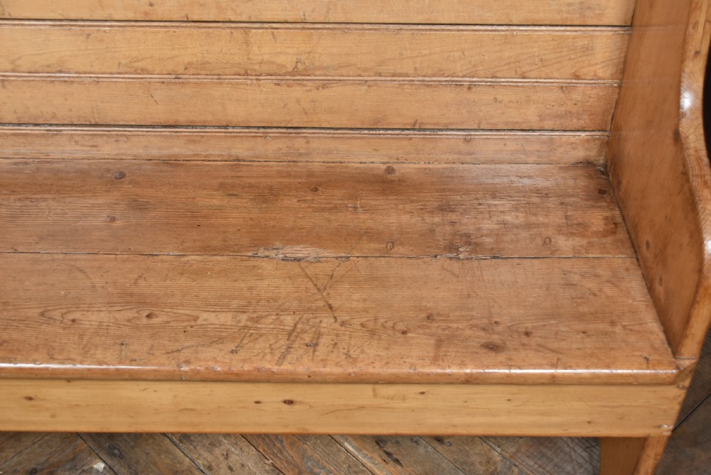 A high-backed antique pine tavern bench featuring horizontal panelled construction and shaped side supports. View VII
