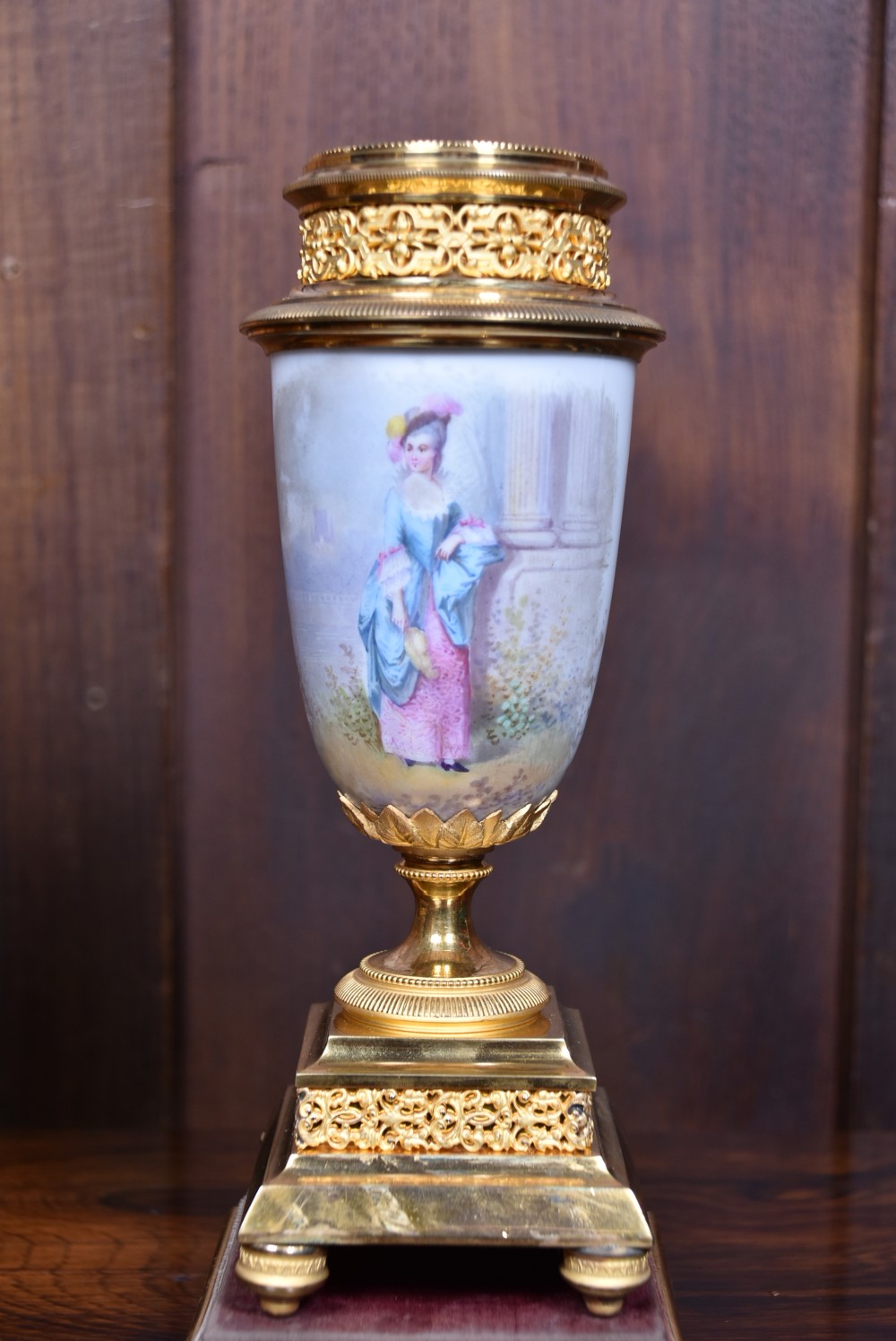A three-piece antique French gilt metal and painted porcelain clock garniture set with matching side urns, each housed under a glass dome on a black base. View XVII