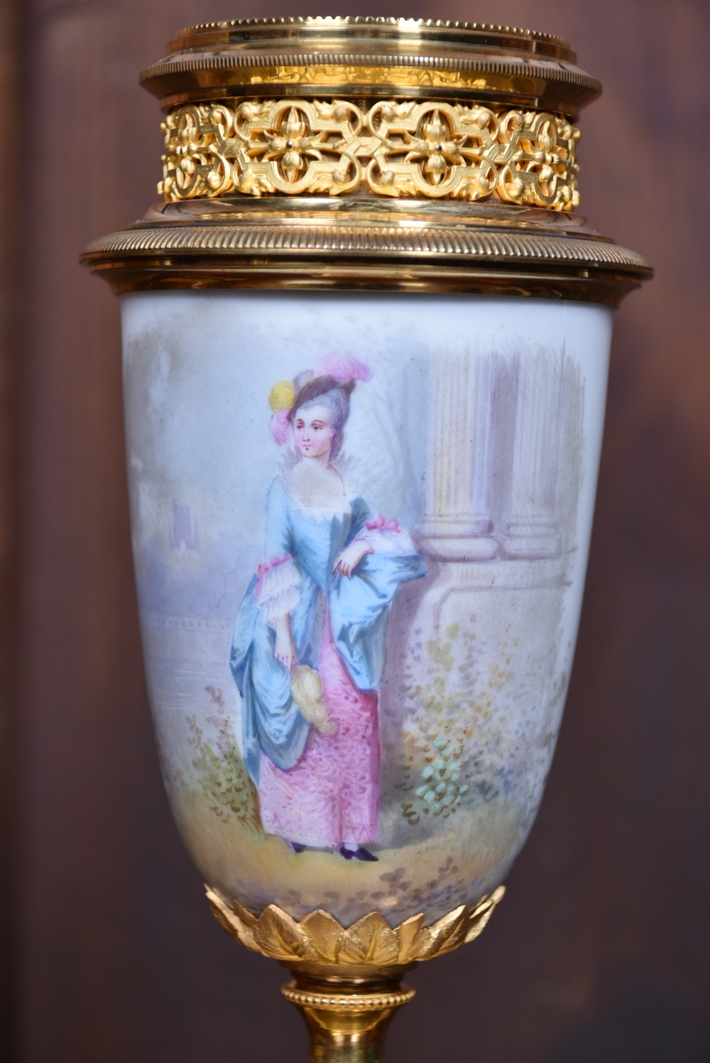 A three-piece antique French gilt metal and painted porcelain clock garniture set with matching side urns, each housed under a glass dome on a black base. View XIX